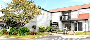 A building with a sign that says "Laurel Cottage" is in front of a tree.