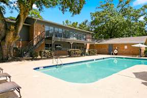 A swimming pool in a backyard with a deck and a tree.