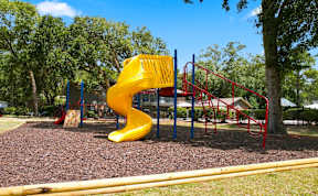 A playground with a yellow slide and red monkey bars.