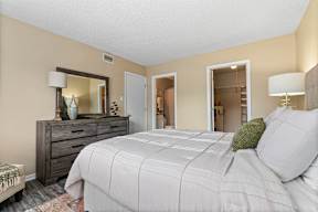 A bedroom with a large bed, a dresser, and a mirror.