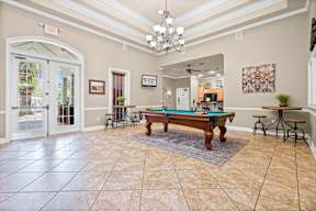 A large room with a pool table and a bar.