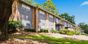 A row of apartment buildings with trees in front.