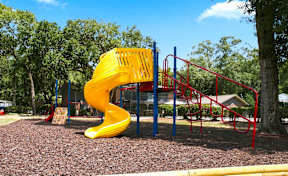 A playground with a yellow slide and red monkey bars.
