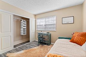 A bedroom with a bed, desk, and chair.