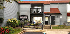 A grey building with a black sign that says Leasing Office.