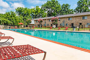 A pool with a red bench and a building in the background.
