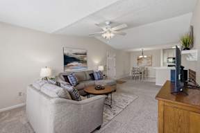 A living room with a grey couch and a painting on the wall.