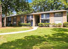 A brick apartment building with a green lawn in front.