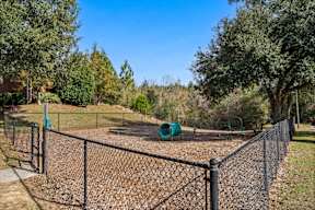 A playground with a green slide and a fence.