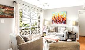 A living room with a couch, chair, and a painting on the wall.