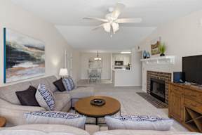 A living room with a grey couch and a painting on the wall.
