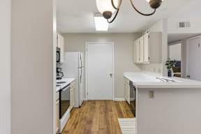 A kitchen with white appliances and wooden floors.