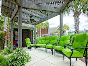 outdoor chairs with green cushions under a pavilion