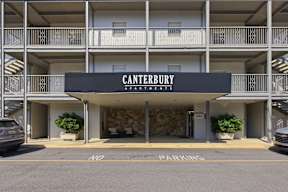 The Canterbury Apartments building has a parking area in front.