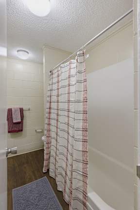 A shower curtain with a red and white checkered pattern hangs in a white bathroom.