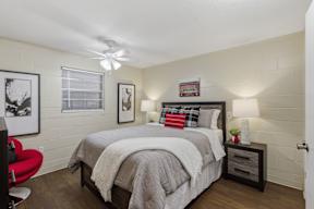 A bedroom with a bed, a chair, and a ceiling fan.