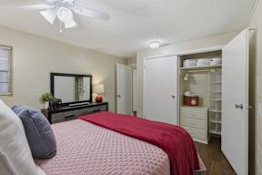 A bedroom with a bed, dresser, and a ceiling fan.
