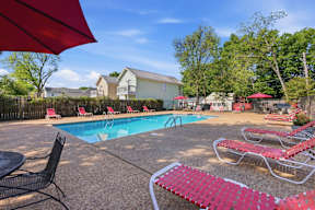 A pool area with red lounge chairs and umbrellas.