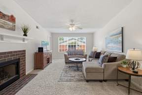 A living room with a fireplace and a ceiling fan.