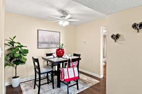 A dining room with a table, chairs, and a ceiling fan.
