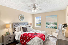 A bedroom with a bed covered in a red Alabama football comforter.