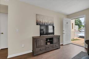 A room with a tv on a cabinet and a painting on the wall.