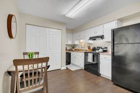 A kitchen with a black fridge and white cabinets.