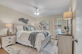 A bedroom with a bed, nightstands, and a ceiling fan.