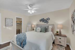 A bedroom with a bed, nightstand, and a ceiling fan.