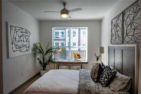 A bedroom with a bed, a ceiling fan, and a window with blinds.