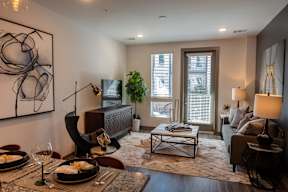 A modern living room with a dining table set for two.