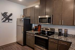 A modern kitchen with dark brown cabinets and stainless steel appliances.