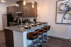 A kitchen with a bar stool and a painting on the wall.