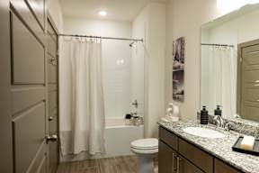 A bathroom with a white shower curtain and a white toilet.