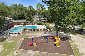 A playground with a red and yellow slide, a blue and yellow swing set, and a green lawn.