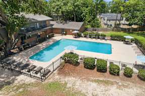 A swimming pool surrounded by a black fence and green bushes.