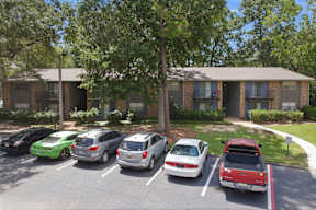 A parking lot with cars and a building in the background.