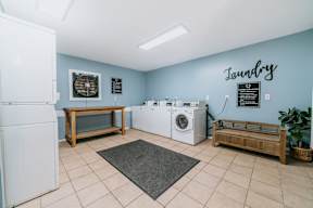 A laundry room with a washer and dryer, a bench, and a fan.