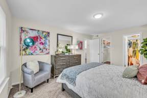 A bedroom with a bed, dresser, and chair.
