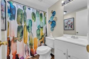 A bathroom with a white toilet and a shower curtain with a watercolor design.