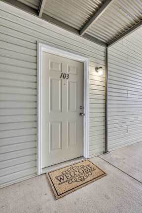 A white door with the number 103 on it and a doormat that says "welcome".