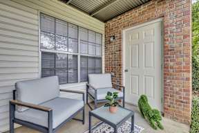 A small patio with a grey couch, a small table and a green plant.