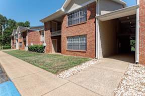the view of a brick apartment building with a sidewalk and grass