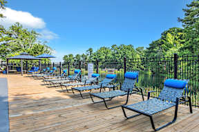 an outdoor deck with chaise lounge chairs and a black fence
