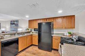 A kitchen with black appliances and wooden cabinets.