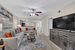 A living room with a grey couch, a coffee table, and a large painting on the wall.
