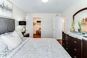 a bedroom with a large bed and a dresser with a mirror