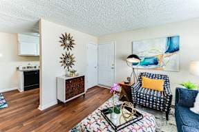 a living room with hardwood floors and a kitchen in the background
