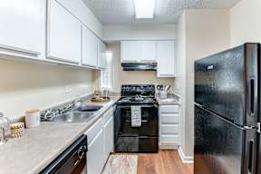 a kitchen with white cabinets and black appliances