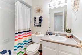 a bathroom with a white sink and toilet next to a shower curtain with a rainbow striped shower